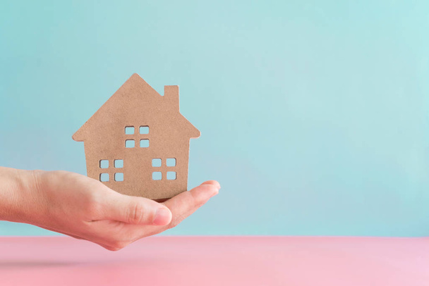 Hand hold home or house model in pastel color room background. Investment wealthy freedom life. - Photo, image