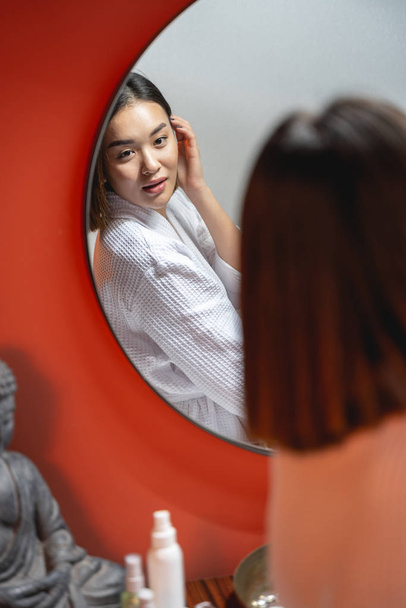 Young pretty Asian girl looking at mirror indoors - Valokuva, kuva