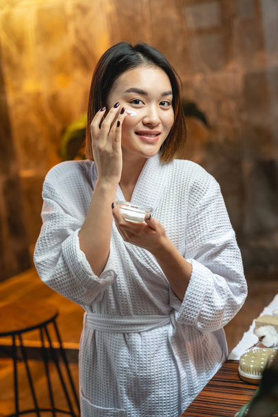 Pretty cute Asian girl applying cream on her skin - Фото, зображення