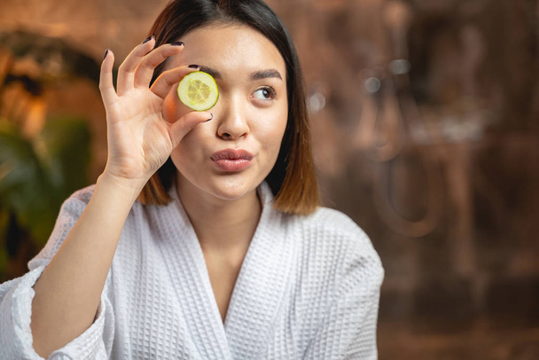 Funny Asian girl posing for camera with slices of cucumber - Fotoğraf, Görsel