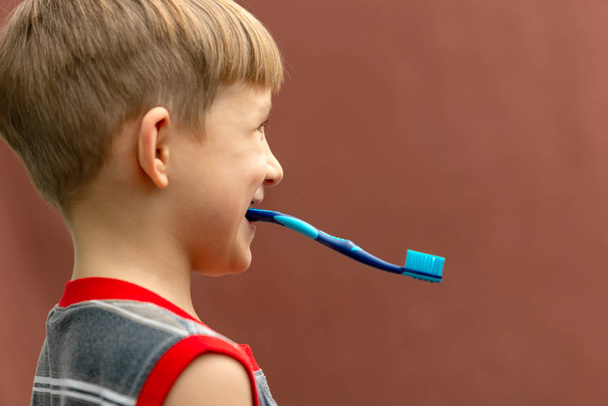 Мальчик держит зубную щетку в зубах с обратной стороны
. - Фото, изображение