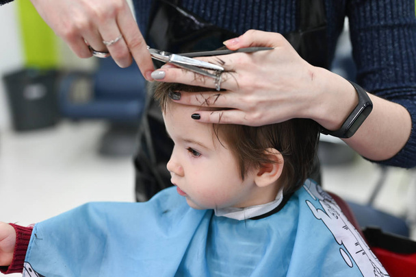 Haircut boy 0-1 years. The first haircut of the child at the hairdresser. Baby haircut toddler. - Фото, зображення