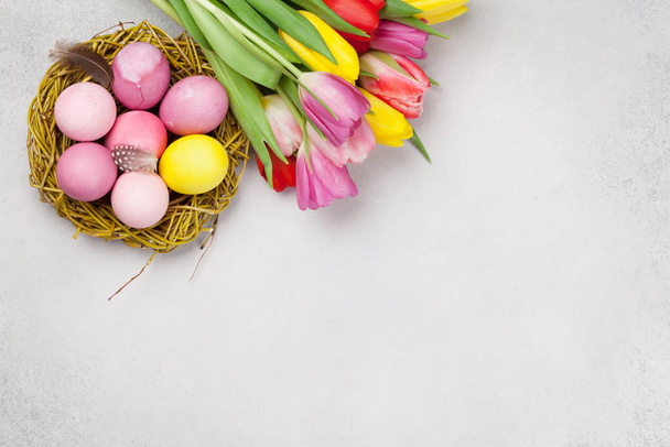 Cartão de Páscoa com ovos de Páscoa e flores de tulipa sobre fundo de pedra. Top vista plana leigos com espaço de cópia - Foto, Imagem
