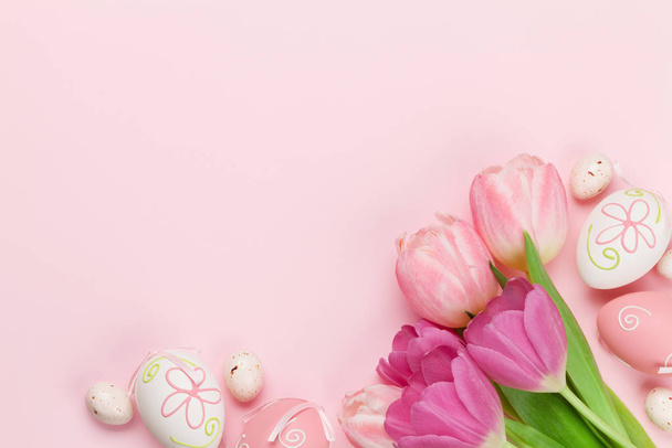 Pasen wenskaart met paaseieren en tulpenbloemen over roze achtergrond. Bovenaanzicht plat lag met kopieerruimte - Foto, afbeelding