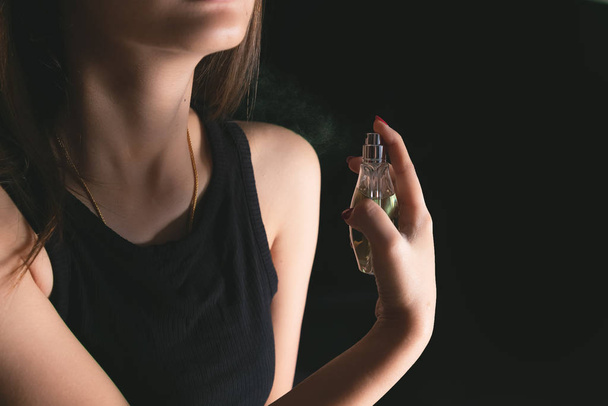 Beautiful young woman with using bottle of perfume. - Фото, изображение