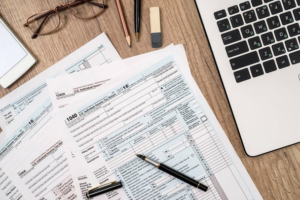 tax form, laptop, coffee and dollar on desk - 写真・画像