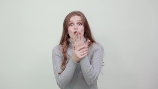 mooie roodharige vrouw in grijze trui met verrassende expressie toont shock - Video