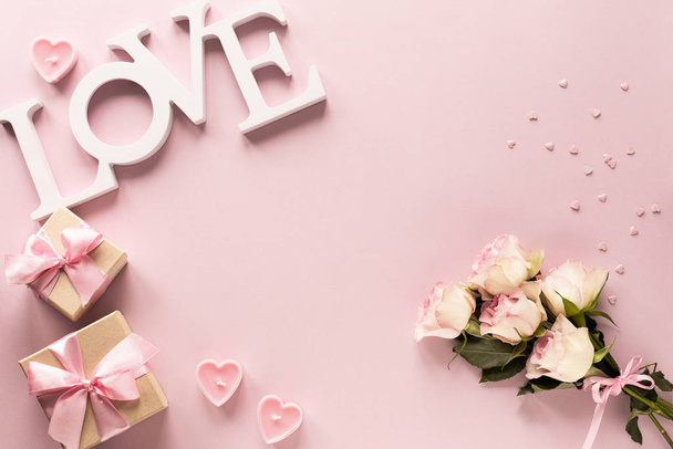 Cadeaudoosje of geschenkdoosje en bloemen op roze tafelblad. Plat gelegd. Verjaardag, bruiloft, Valentijnsdag, 8 maart concept. kopieerruimte - Foto, afbeelding