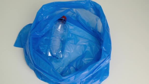 Put a plastic bottle in a trash bag. Close up. - Imágenes, Vídeo