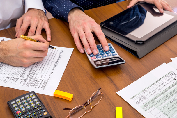 dos hombres llenando USA Tax 1040 Formulario con calculadora, tableta
. - Foto, imagen