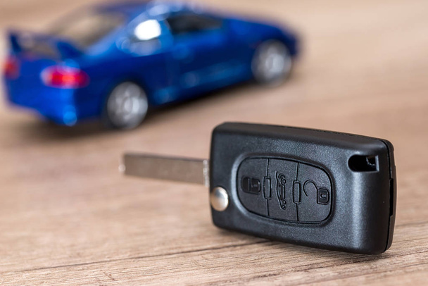car key and  blue car toy on wooden desk. - Photo, Image
