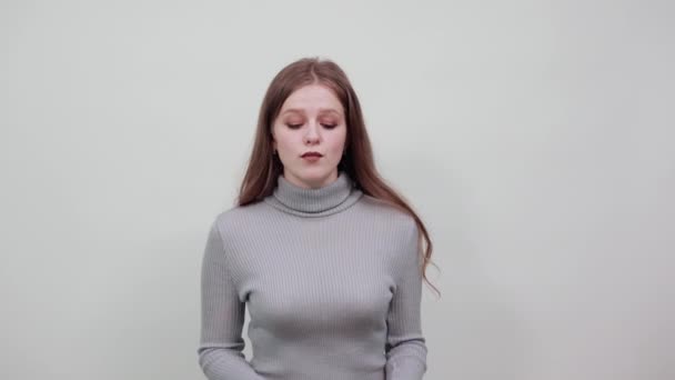  jong mooi meisje met rood haar in grijs trui zet handen over haar oren - Video
