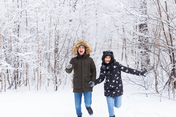 Mutlu çift kışın karlı bir ormanda yürüyor. - Fotoğraf, Görsel