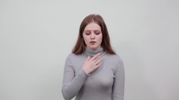 woman in sweater with red hair is bent in pain, holding her neck and throat sore - Imágenes, Vídeo