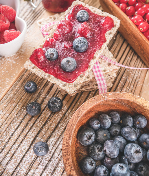 Decorated sweet breakfast with berries and toast over wooden table. Tasty healthy sweet food  - Fotó, kép