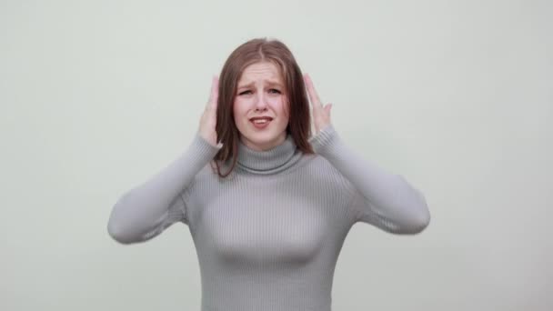 woman in gray sweater holds her head with her hands from surprise fright shock - Footage, Video