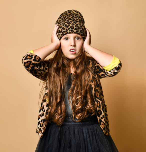 jong plus size meisje model in stijlvolle luipaard gekleurde casual kleding en zwarte rok holding hoofd en het gevoel verrast - Foto, afbeelding