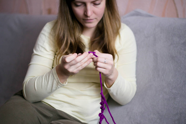 A woman crochets a product from soft, fluffy, purple yarn. Croch - Fotoğraf, Görsel