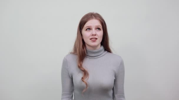 eine junge schöne rothaarige Frau im grauen Pullover zwingt unaufrichtig falsches Lachen - Filmmaterial, Video