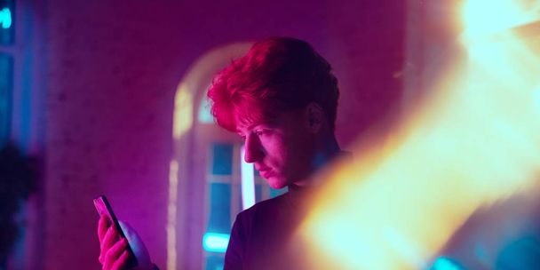 Cinematic portrait of handsome young man in neon lighted interior - Фото, зображення