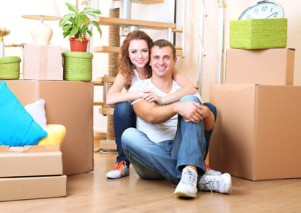 Young couple sitting in new house on staircase background - Foto, Imagem