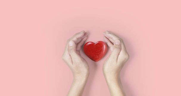 Vörös szívet, szívegészségügyet és adományozási fogalmakat tartó kezek - Fotó, kép