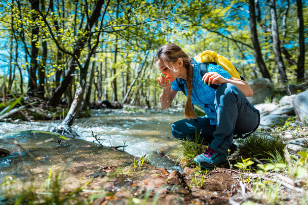 Femme se rafraîchissant avec de l'eau fraîche du ruisseau pendant la randonnée
 - Photo, image