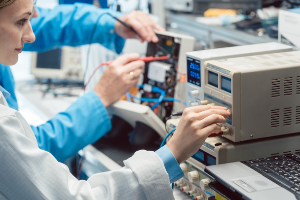 Kaksi elektronista insinööriä testipenkissä mittaamassa uutta tuotetta - Valokuva, kuva