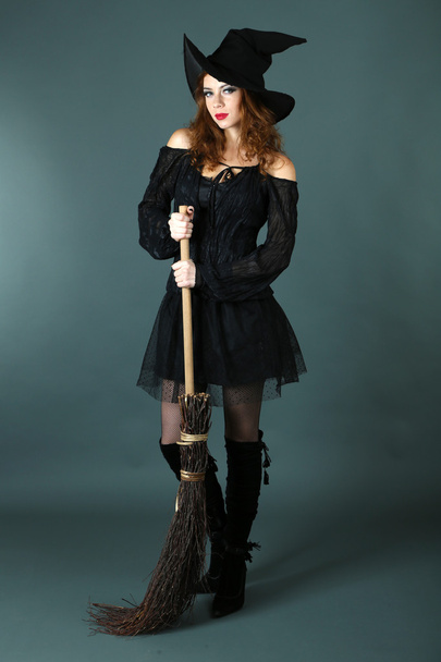 Halloween witch with broom on gray background - Foto, afbeelding
