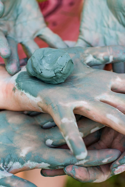 Child models handicraft in lump of clay by hands - Foto, afbeelding