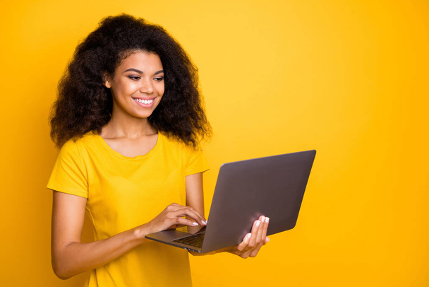 Close-up portrait of her she nice attractive lovely cheerful wavy-haired girl holding in hands laptop creating project isolated over bright vivid shine vibrant yellow color background - Foto, imagen