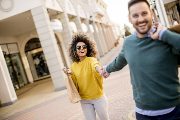 Beau jeune couple multiethnique avec des sacs en papier profitant dans le shopping et s'amusant dans la ville
 - Photo, image