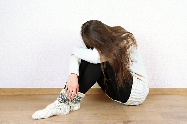 Sad woman sitting on floor near wall - Φωτογραφία, εικόνα