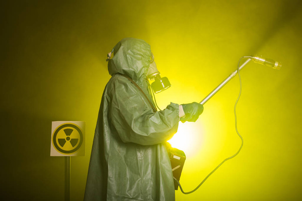 Säteily ja vaara käsite Ihminen kaasunaamarissa ja kemiallisessa puvussa. Radioaktiivisuutta mittaava työntekijä
 - Valokuva, kuva