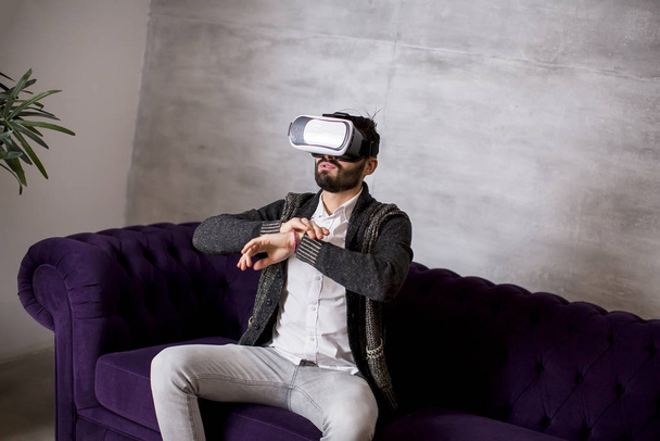 Beau jeune homme barbu portant des lunettes de réalité virtuelle dans la chambre moderne
 - Photo, image