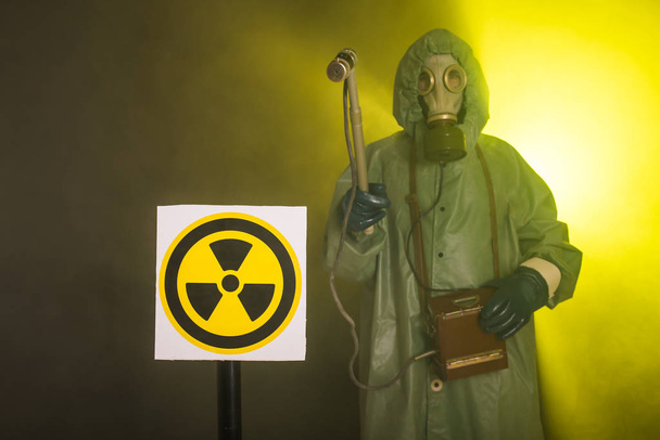 Ακτινοβολία και κίνδυνος έννοια - Ο άνθρωπος με τη μάσκα αερίου και χημική στολή. Ο εργαζόμενος που κάνει μέτρηση ραδιενέργειας - Φωτογραφία, εικόνα