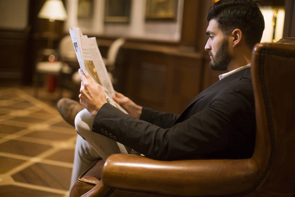Modern handsome young businessman reading newspapers in the room - Photo, Image