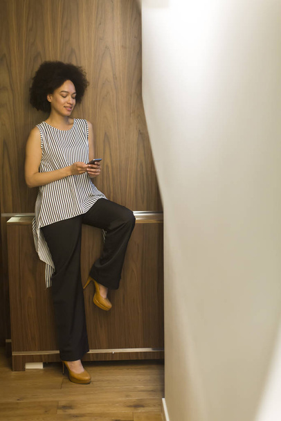 Smiling young african american businesswoman using mobile phone in office - Foto, Imagem