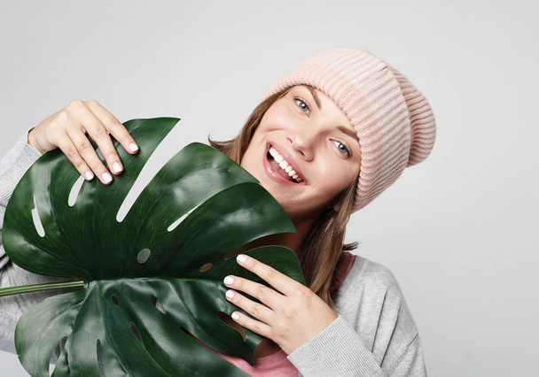 Beautiful young woman holding a leaf of a large tropical flower and smiling - Foto, Imagem