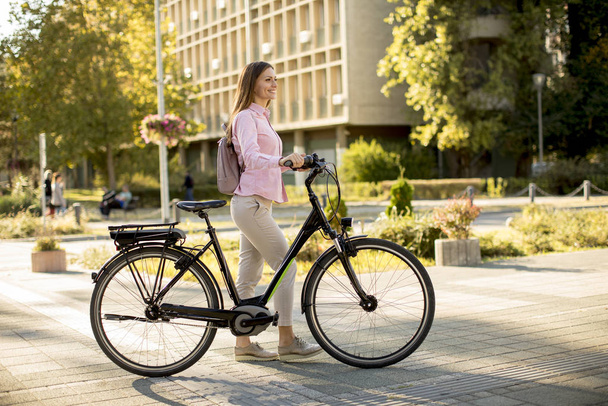 Красивая молодая женщина с современным городским электрическим электронным велосипедом экологически чистый городской транспорт
 - Фото, изображение