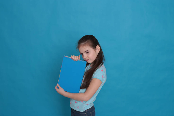 Wesoła kochająca dziewczyna w wieku ośmiu lat i kolorowy arkusz papieru wolne miejsce do nagrywania na niebieskim tle - Zdjęcie, obraz