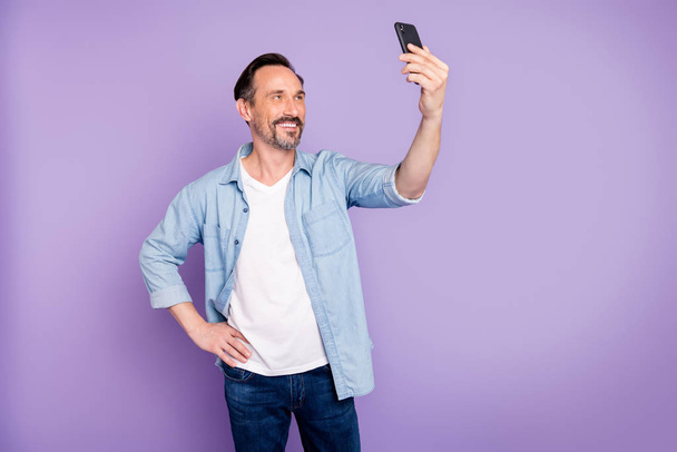 Portrait of charming candid man travel journey on spring time make selfie with his cell phone wear good looking clothes isolated over purple color background - Zdjęcie, obraz