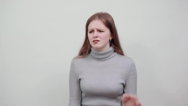 Una chica joven en suéter gris es difícil de oír y sostiene la mano cerca de la oreja
. - Metraje, vídeo