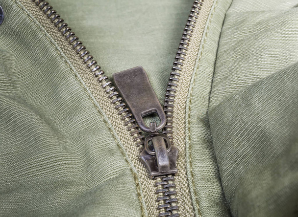 Fragment of metal zipper on outerwear olive color close-up - Photo, Image