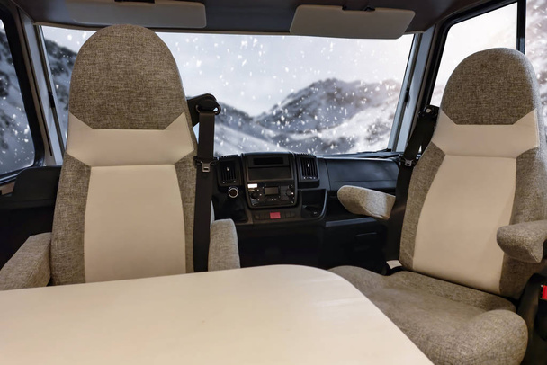 Car Camper travel in winter time. Interior of camper with big window winter view. Empty space for your decoration.Cold december day and landscape of mountains. Snowy winter mountain background. Beautiful top view of Alps in Austria.  - Photo, image