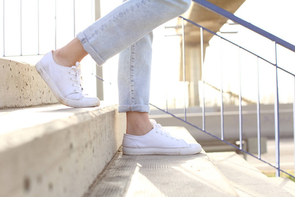 Perfil de pernas de mulher vestindo tênis descendo escadas
 - Foto, Imagem