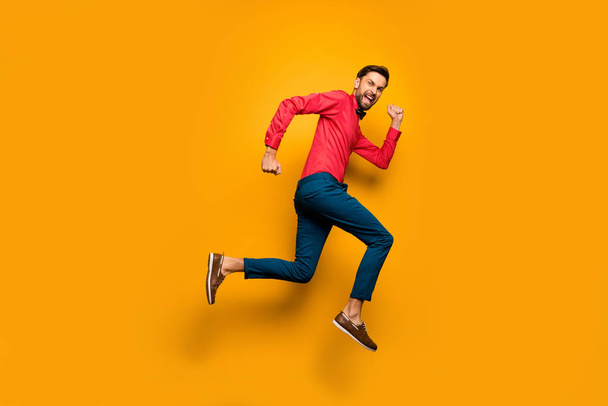 Full size profile photo of funny guy jump high up rush black friday shopping center wear trendy red shirt bow tie pants shoes outfit isolated yellow color background - Foto, imagen