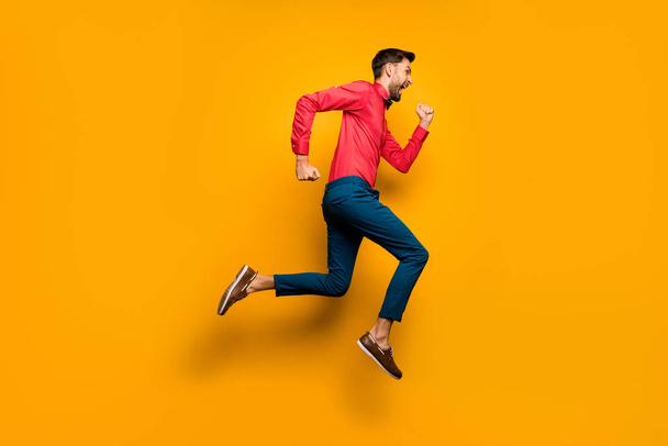Full length profile photo of crazy funny guy jumping high up rushing black friday shopping wear trendy red shirt bow tie pants shoes outfit isolated yellow color background - Zdjęcie, obraz