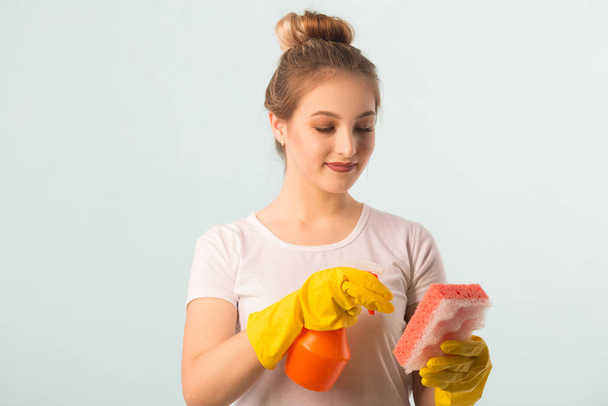 beautiful young woman in rubber gloves with a sponge and a spray for cleaning - Fotoğraf, Görsel
