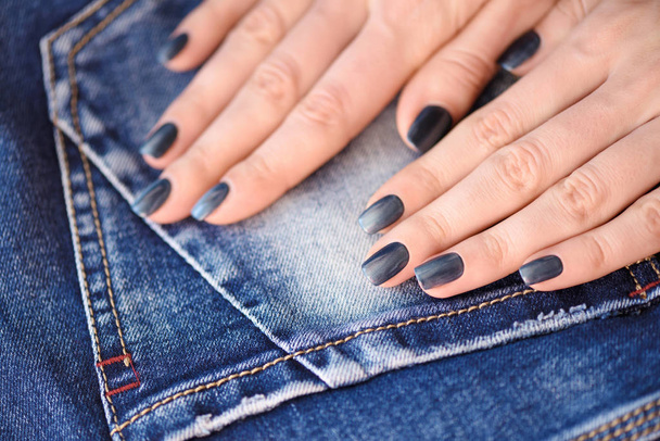 Ręce z ciemny niebieski wypielęgnowane paznokcie na tło włókienniczych dżinsy - Zdjęcie, obraz